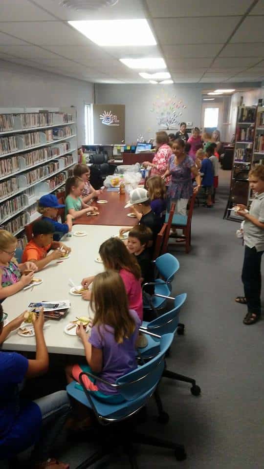 A dozen young kids participating in a library craft project.